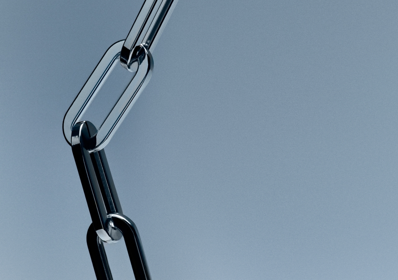 Artistic 3D image of metallic chain links on a light blue-gray gradient background